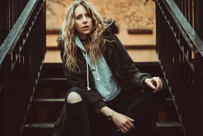 Portrait of young woman sitting on steps in city