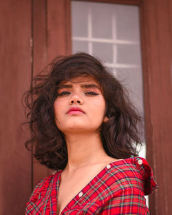 Portrait of beautiful young woman against door