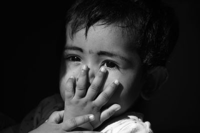 Close-up portrait of baby girl over black background