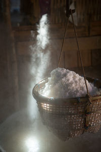 Close-up of rice in wicker basket above water in container with steam