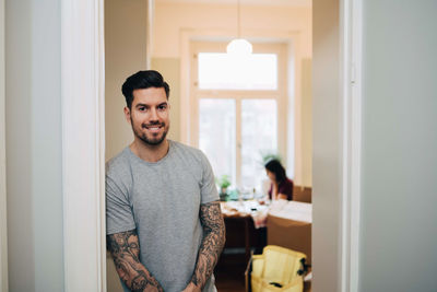 Portrait of smiling man leaning on doorway at new home