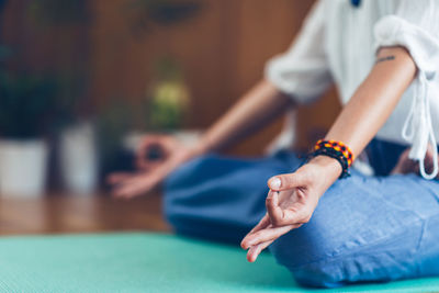 Midsection of young woman doing yoga on exercise mat