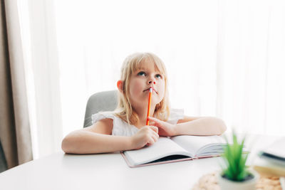 Portrait of young woman sitting on table at home