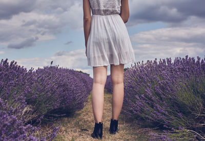 Low section of woman standing on field against sky