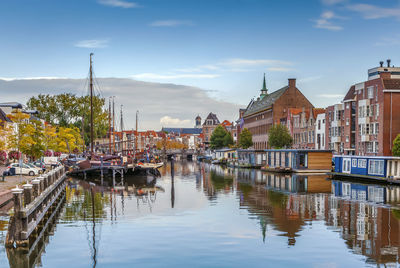 Sailboats in river amidst buildings against sky