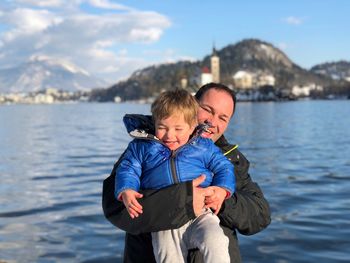 Portrait of father and son standing at beach against sky