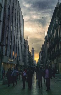 People walking on street in city against sky