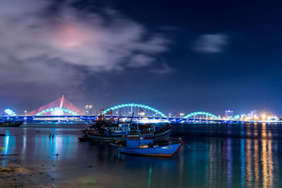 Illuminated bridge over sea against sky at night