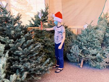 Full length of girl standing by christmas tree