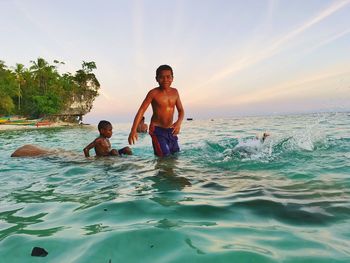 Portrait of shirtless man in sea against sky