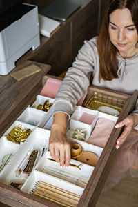 High angle view of woman arranging stationary in drawer