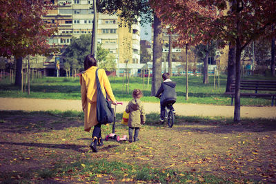 Rear view of mother with kids spending leisure time at park