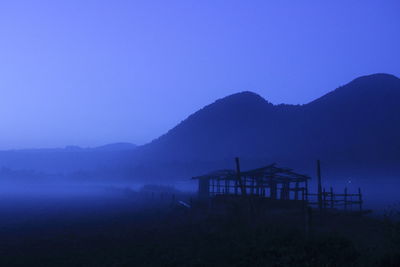 Silhouette built structure on beach against blue sky