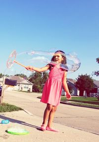 Full length of woman with bubbles standing against sky