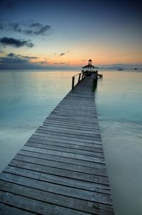 Pier over sea against sky during sunset