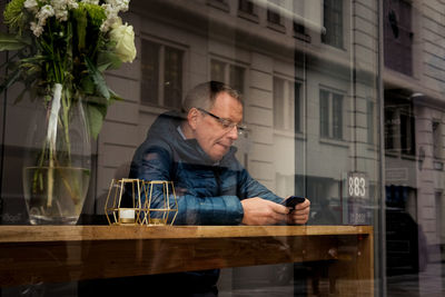 Man using mobile phone while sitting on table