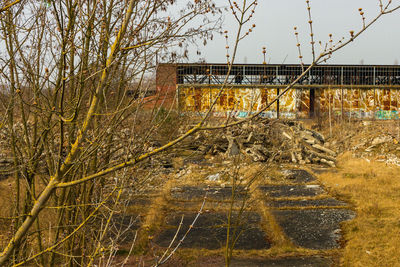 Abandoned bridge amidst trees on field against sky