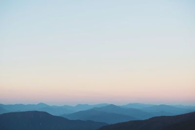 Scenic view of silhouette mountains against clear sky during sunset