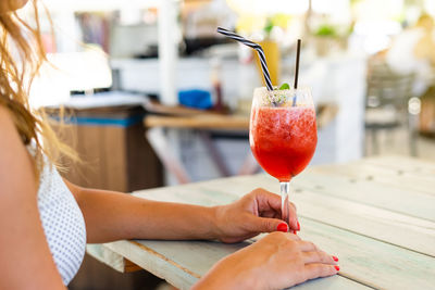 Midsection of woman holding drink on table