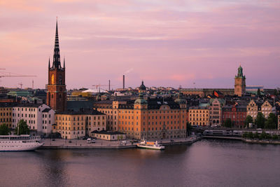 River amidst buildings against sky during sunset