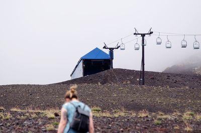 Girl with backup climbing the base of villarrica volcano on a foggy day and view of the lift chairs.