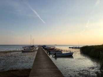 Sailboats moored on sea against sky