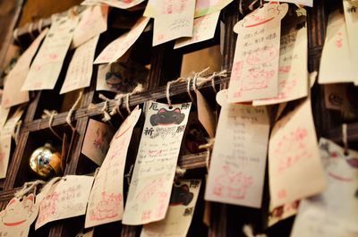 Close-up of papers hanging on railing at shrine