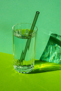 Reusable glass straws in glass with water on green background eco-friendly drinking straw set with