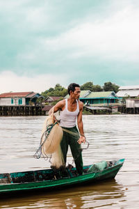 Young man in boat against sky