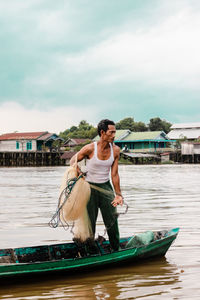 Young man in boat against sky