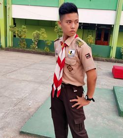 Boy wearing uniform standing against building