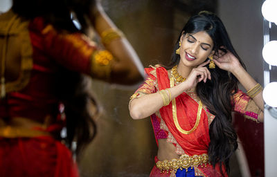 Beautiful woman wearing sari reflecting at mirror