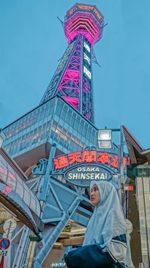 Low angle view of people at amusement park against sky