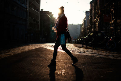 Full length of woman walking on street in city against sky