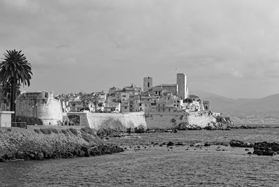 Buildings by sea against sky