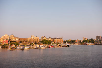 Buildings by river against clear sky in city