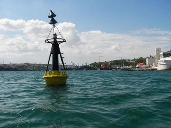 Sailboat in sea by buildings against sky