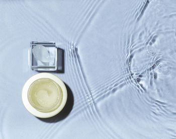 Swatch of cream on glass podium with a jar on water background. concept of moisturizing cosmetics