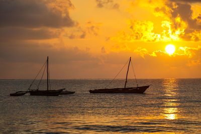 Sailboats in sea against sky during sunset