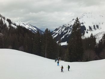 People skiing on snowcapped mountain against sky