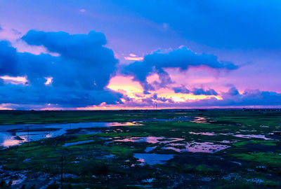 Scenic view of landscape against dramatic sky during sunset