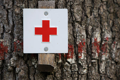 Close-up of sign on tree trunk against wall