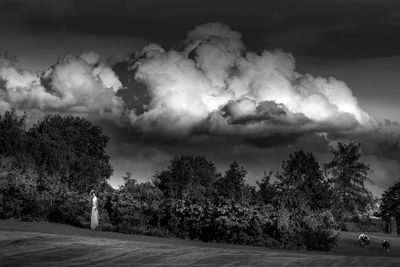 Road by trees against storm clouds