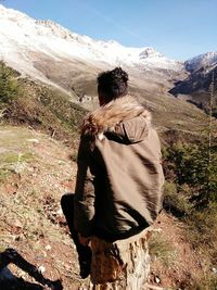 Rear view of man standing on mountain against sky