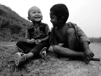 Close-up of cheerful boys sitting on field