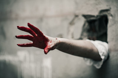 Close-up of hand covered in blood through wall