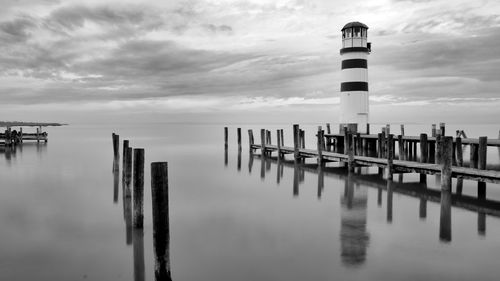 Wooden posts on pier over sea against sky