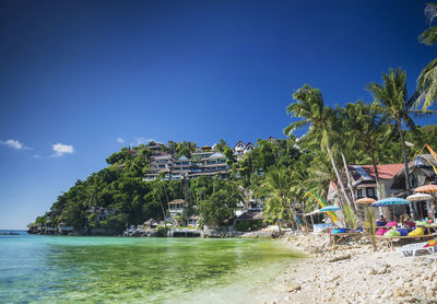 Palm trees by swimming pool against sea and sky