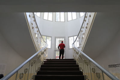 Rear view of man standing on staircase in building