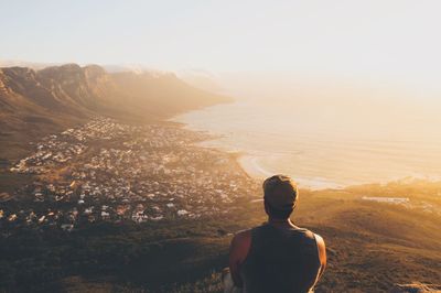 Rear view of man on landscape against sky during sunset